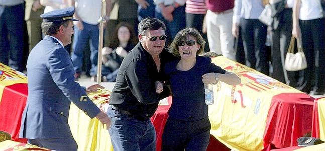 A relative of one of the 62 Spanish peacekeepers who died in an air crash is comforted on the tarmac during a funeral service at the Torrejon's air base, near Madrid, May 28, 2003. A Ukranian Yak-42 plane which was carrying the 62 Spanish peacekeepers and 13 crew returning from Afghanistan crashed near the Turkey's Black Sea city of Trabzon early May 26, as it tried to land in dense fog, killing all aboard. REUTERS/Sergio Perez